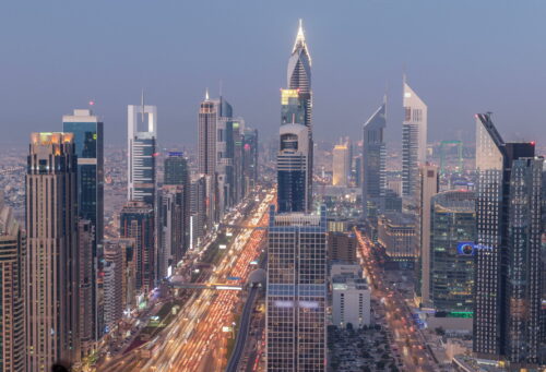 Dubai downtown skyline day to night transition . Rooftop view of traffic on Sheikh Zayed road with numerous illuminated towers.