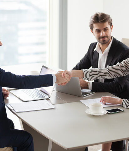Businessman handshaking businesswoman making deal finishing group negotiations, satisfied smiling business partners conclude contract agreement shake hands expressing respect thank for group meeting